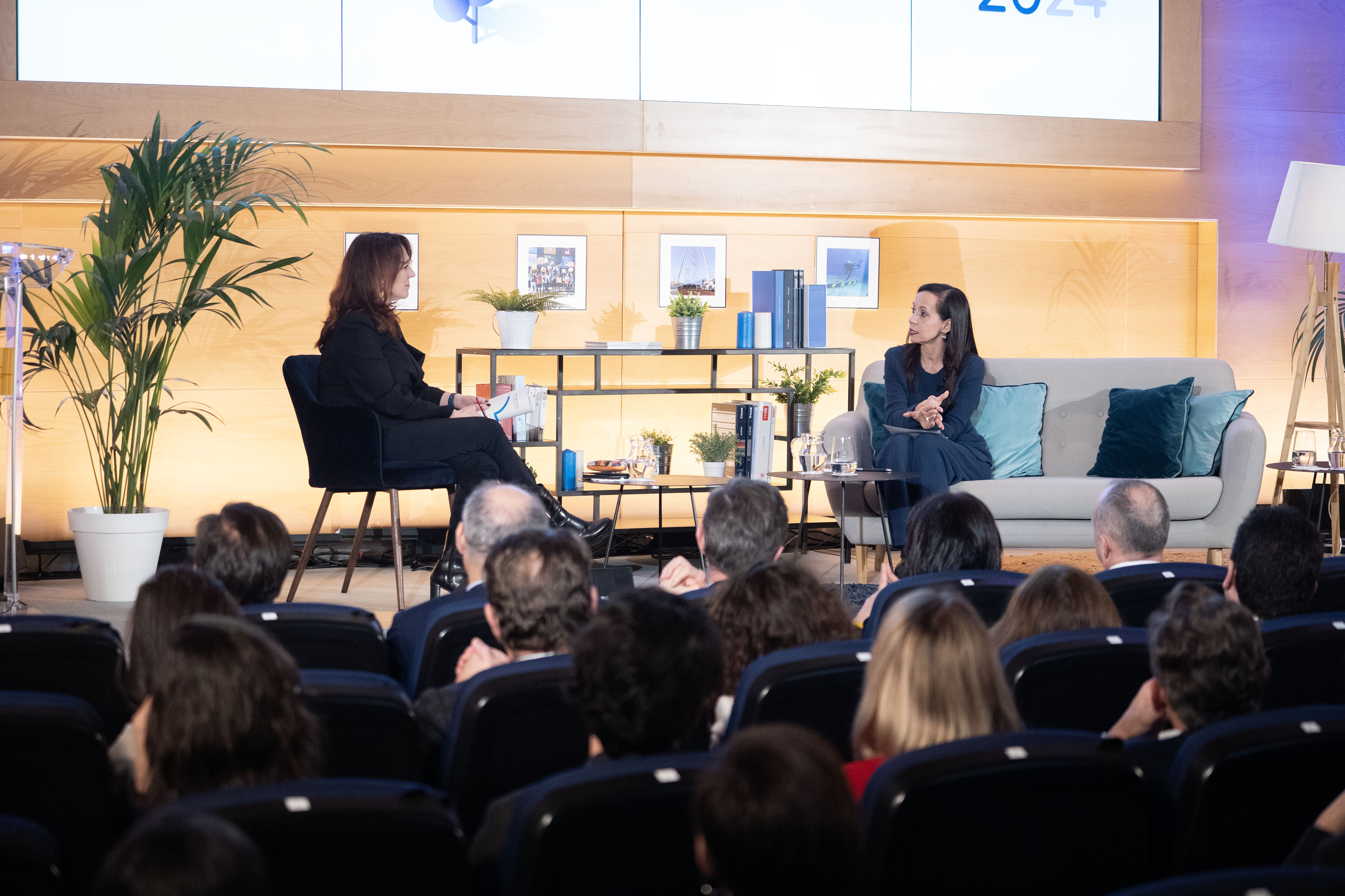 Dos personas charlas en un escenario delante de público en un evento