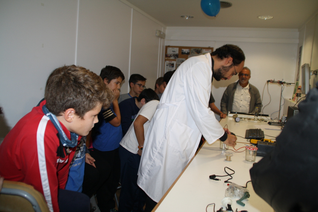 Un monitor del taller científico enseña a los alumnos de un colegio de Alcañiz (Teruel) un experimento con materiales que emiten luz.