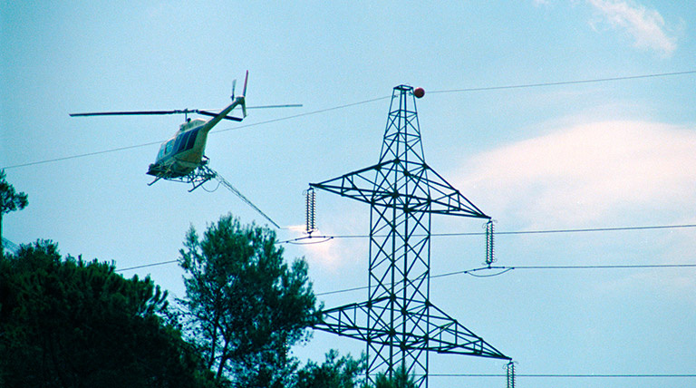 Helicoptero al lado de una torre de alta tensión Abrir documento en nueva ventana