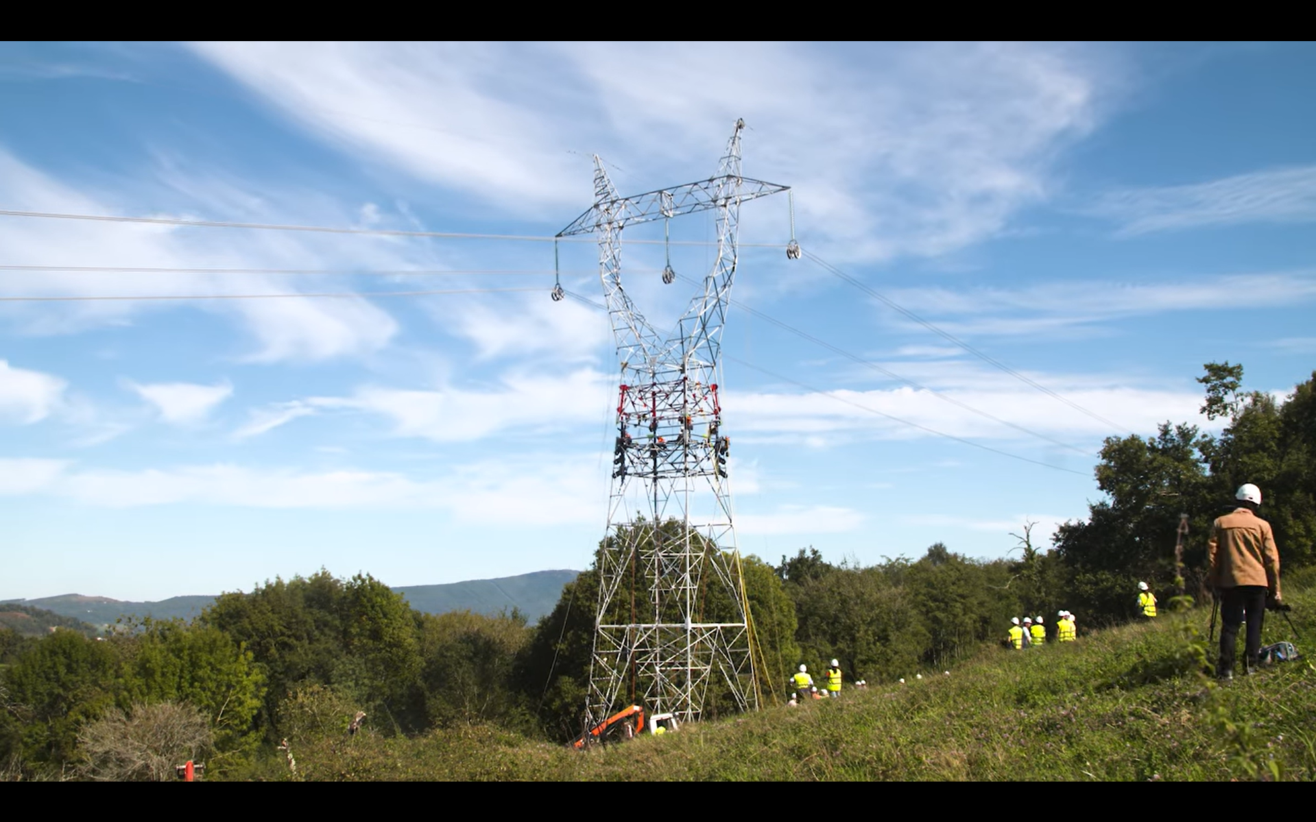 Torre eléctrica en mitad del campo con gente trabajando