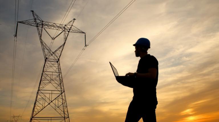 Electrical tower and worker with laptop