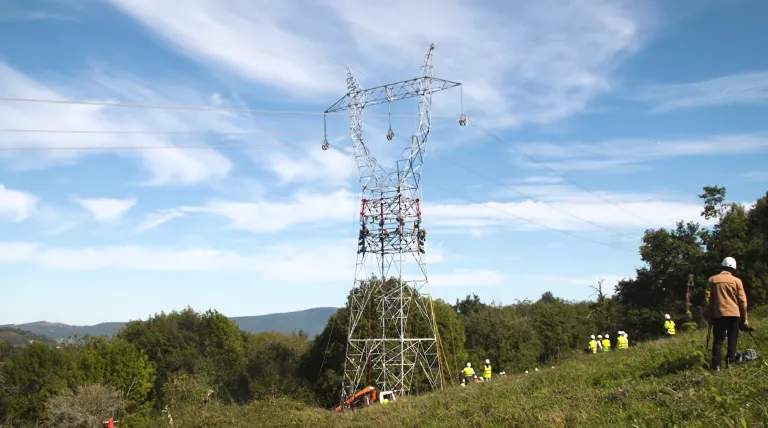 Torre eléctrica en mitad del campo con gente trabajando