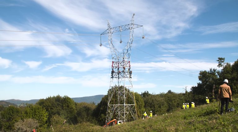 Torre eléctrica en mitad del campo con gente trabajando
